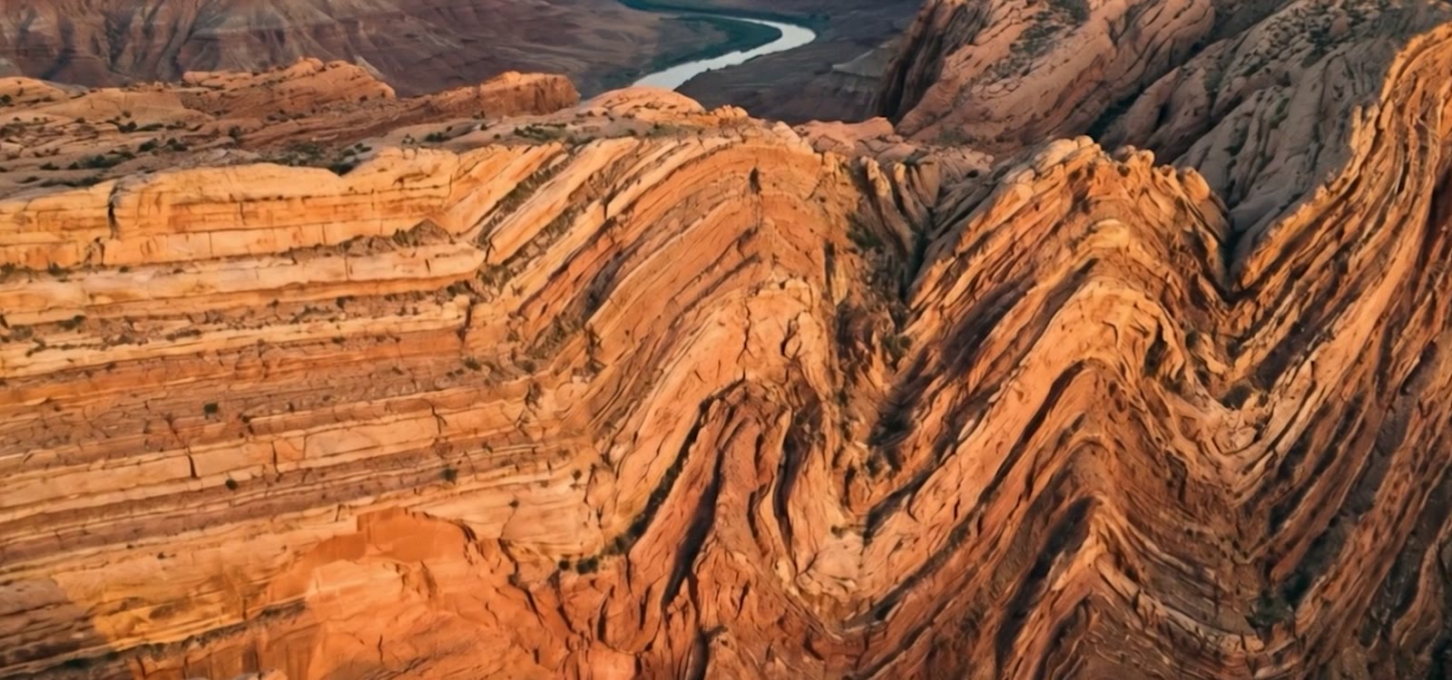 Cinematic aerial of dramatically folded rock strata carved by erosion.
